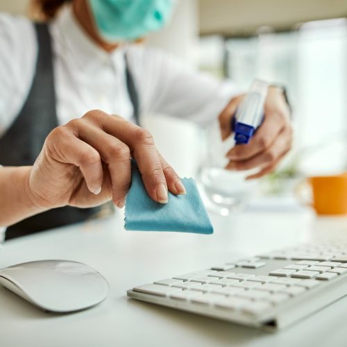 closeup-businesswoman-disinfecting-computer-keyboard-office